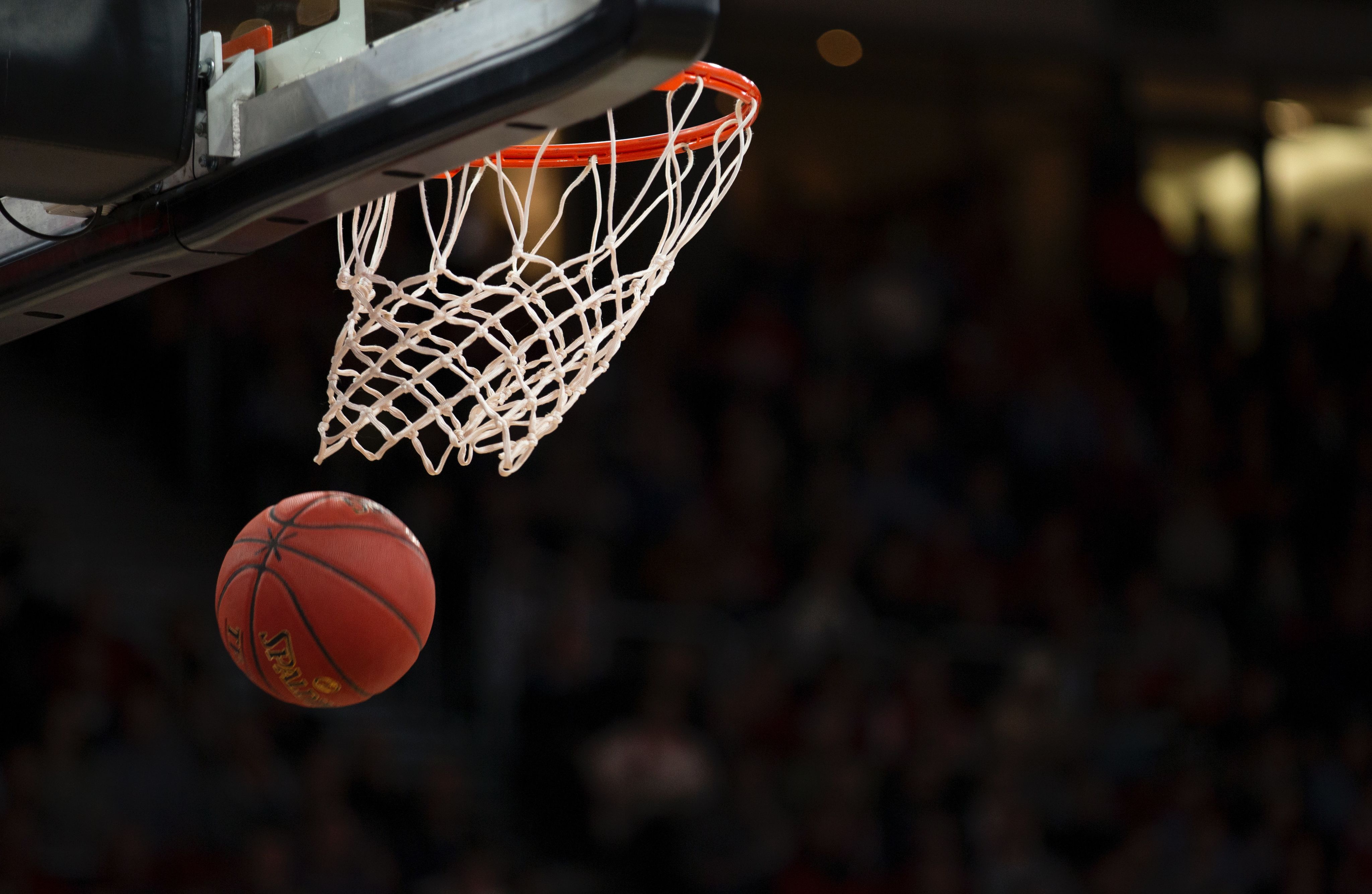 Photo of a basketball coming through a hoop.