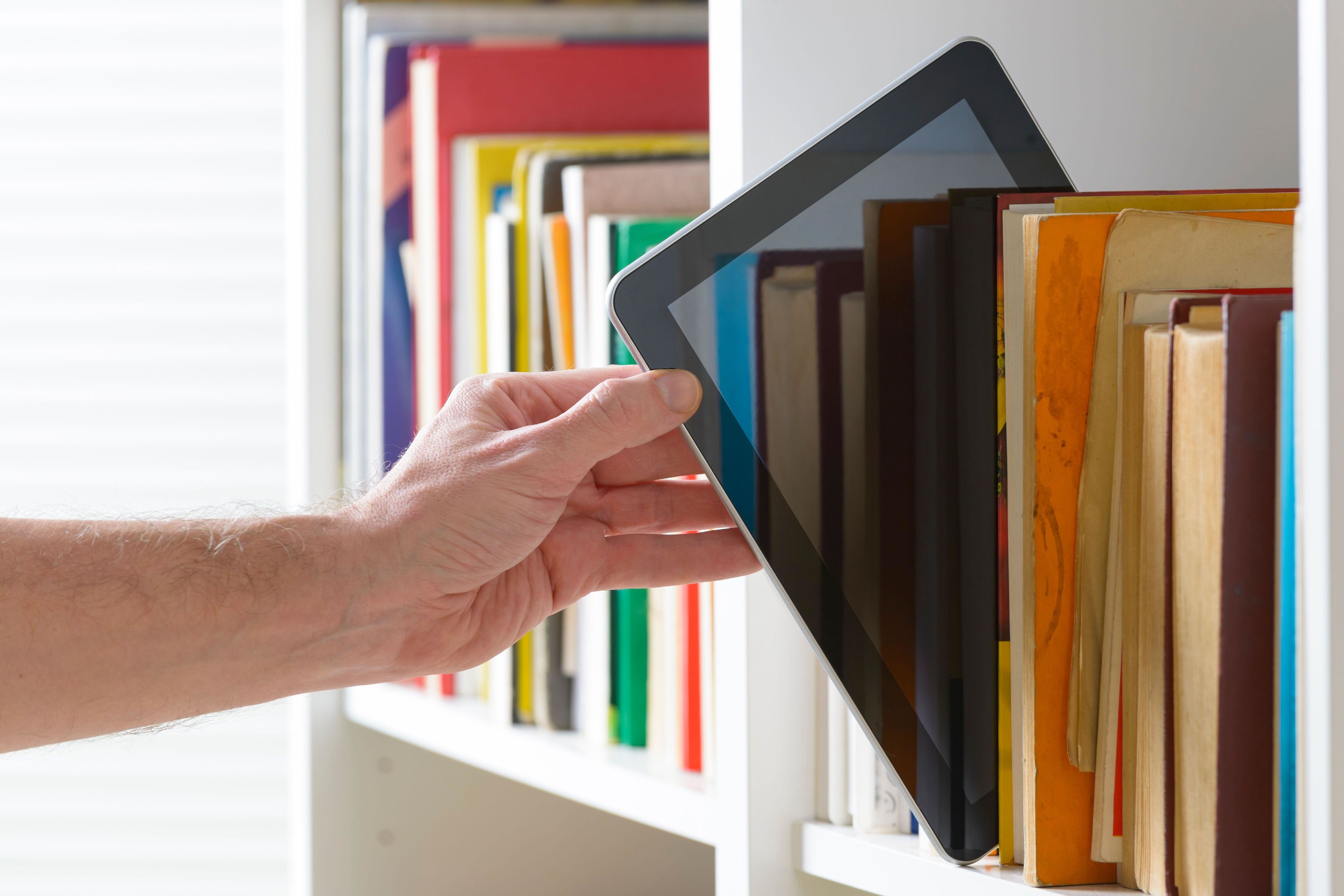 Man reaching for ereader from bookshelf