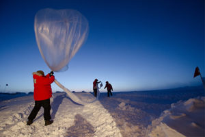 Two researchers release a weather balloon in low light.