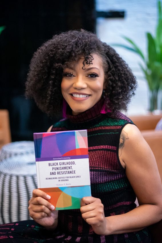 Image of Dr. Nishaun T. Battle holding the book she authored.