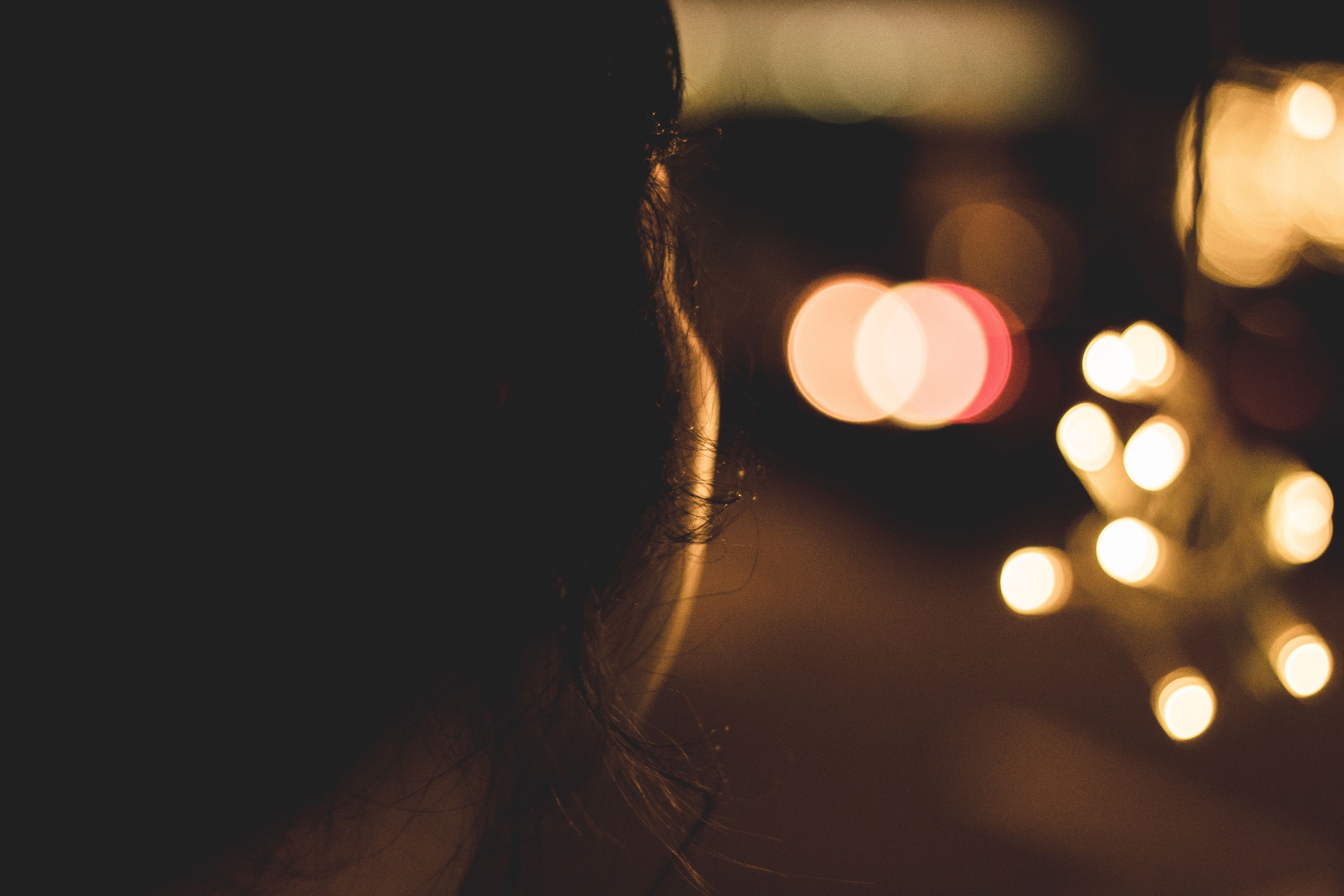 Photo of a person's face in silhouette looking at lights with a dark background