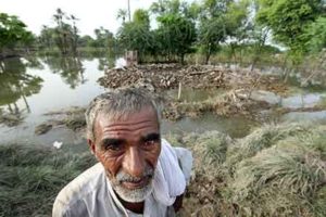 An older man stands in front of the remains of his house following flooding in Pakistan