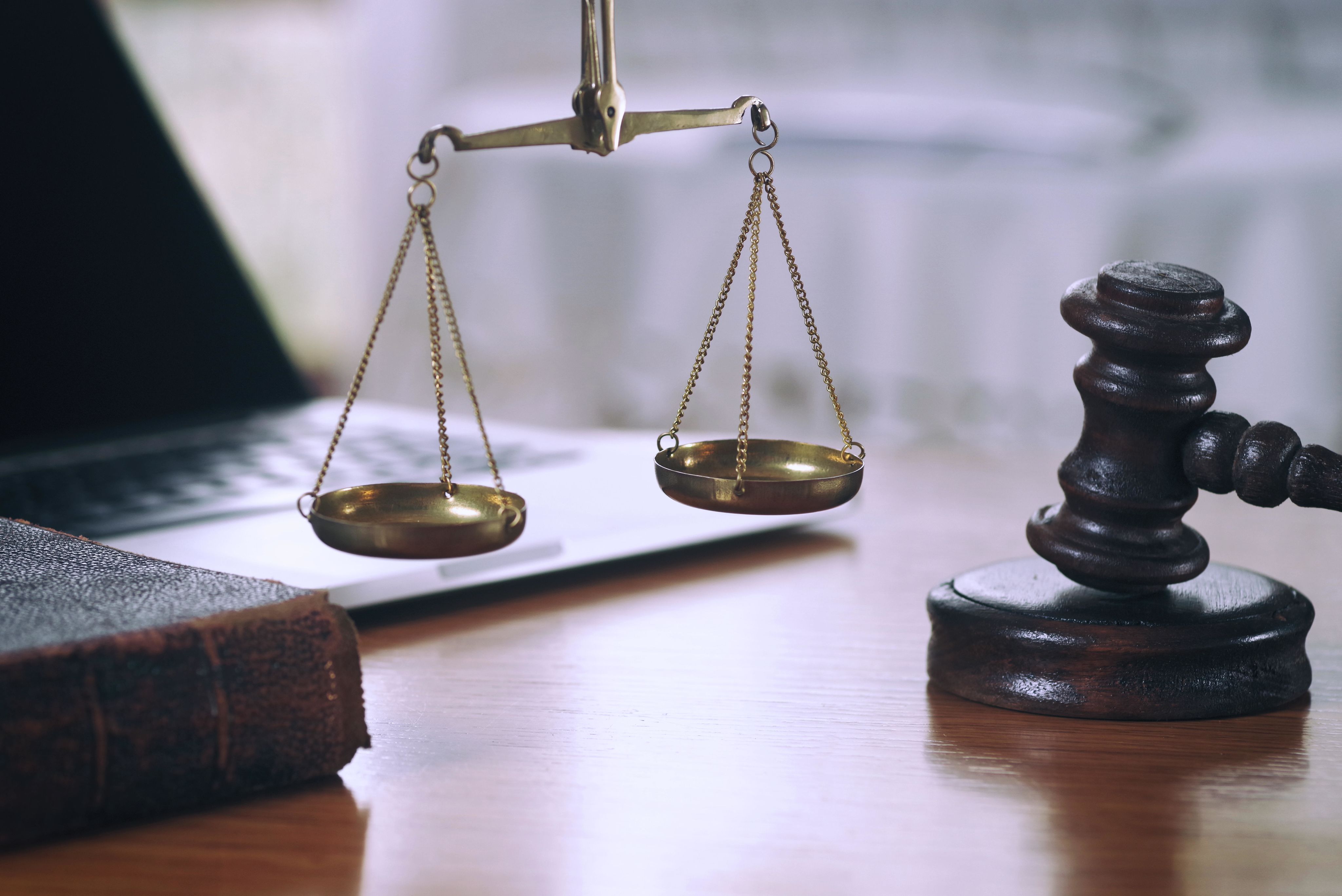 Symbols of the legal system, gavel, book, and scales of justice.