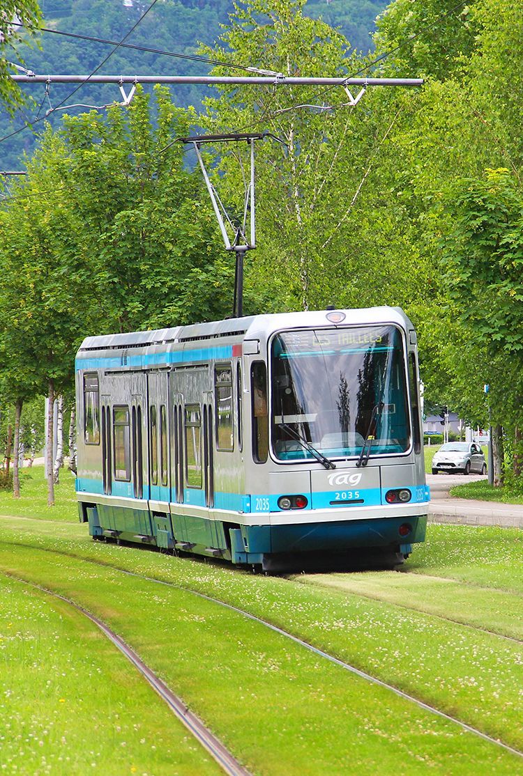 Tram running over grass-covered rails in Grenoble, France
