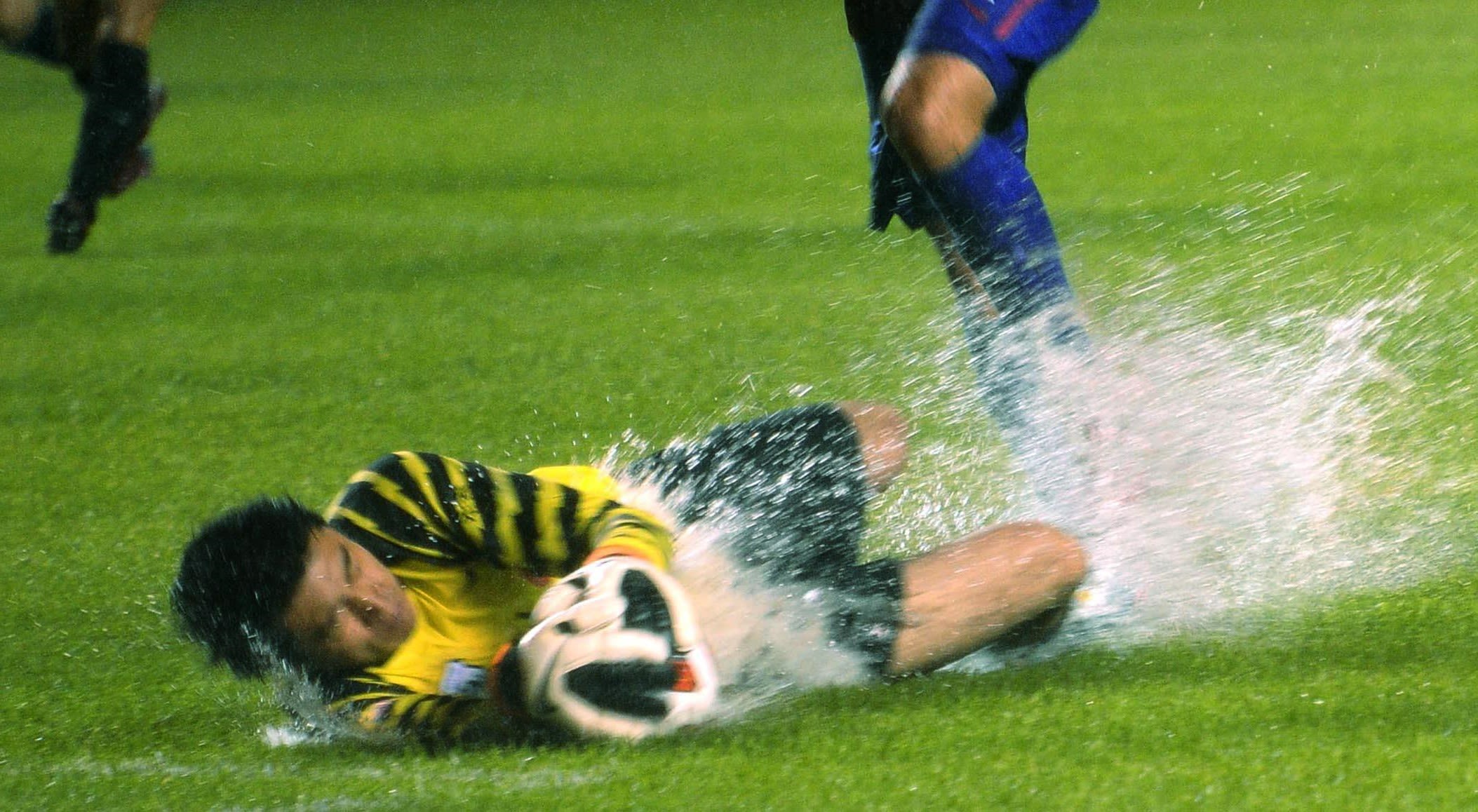 Footballers on a waterlogged pitch during a Typhoon
