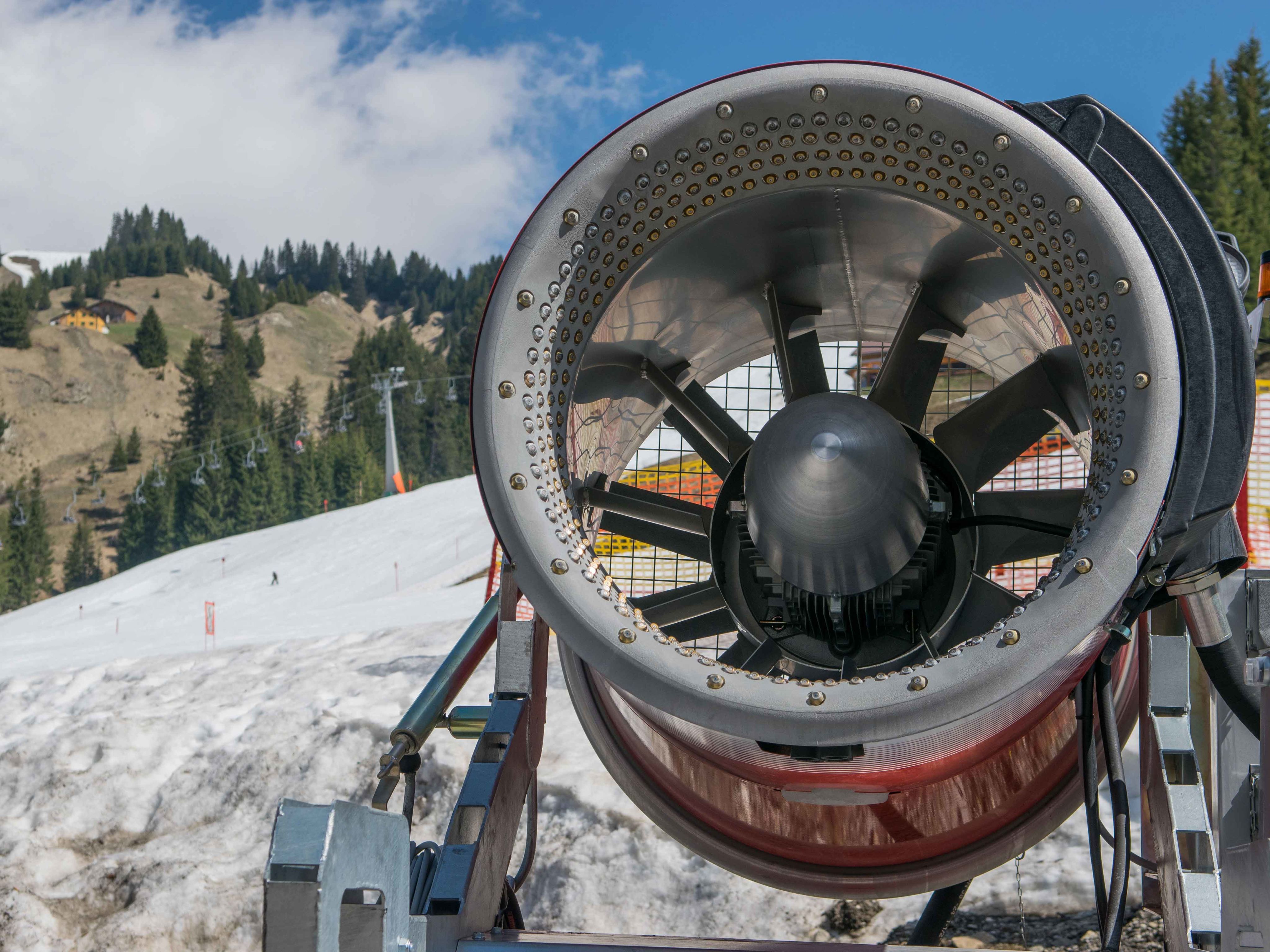 A snow cannon on a ski slope with little snow