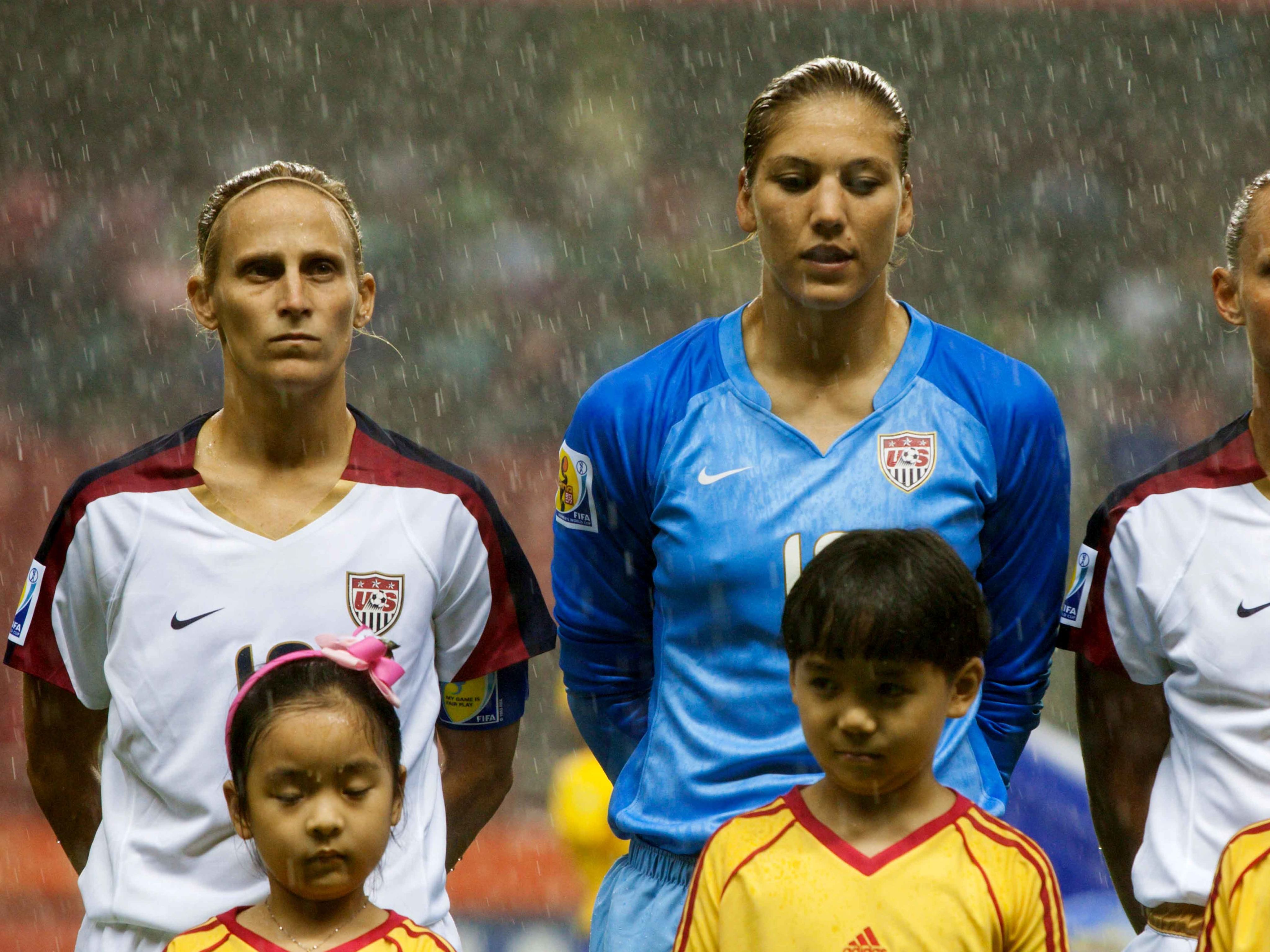 USA team players Kristine Lilly, Hope Solo and Christie Rampone stand during team introductions before a World Cup match in the rain