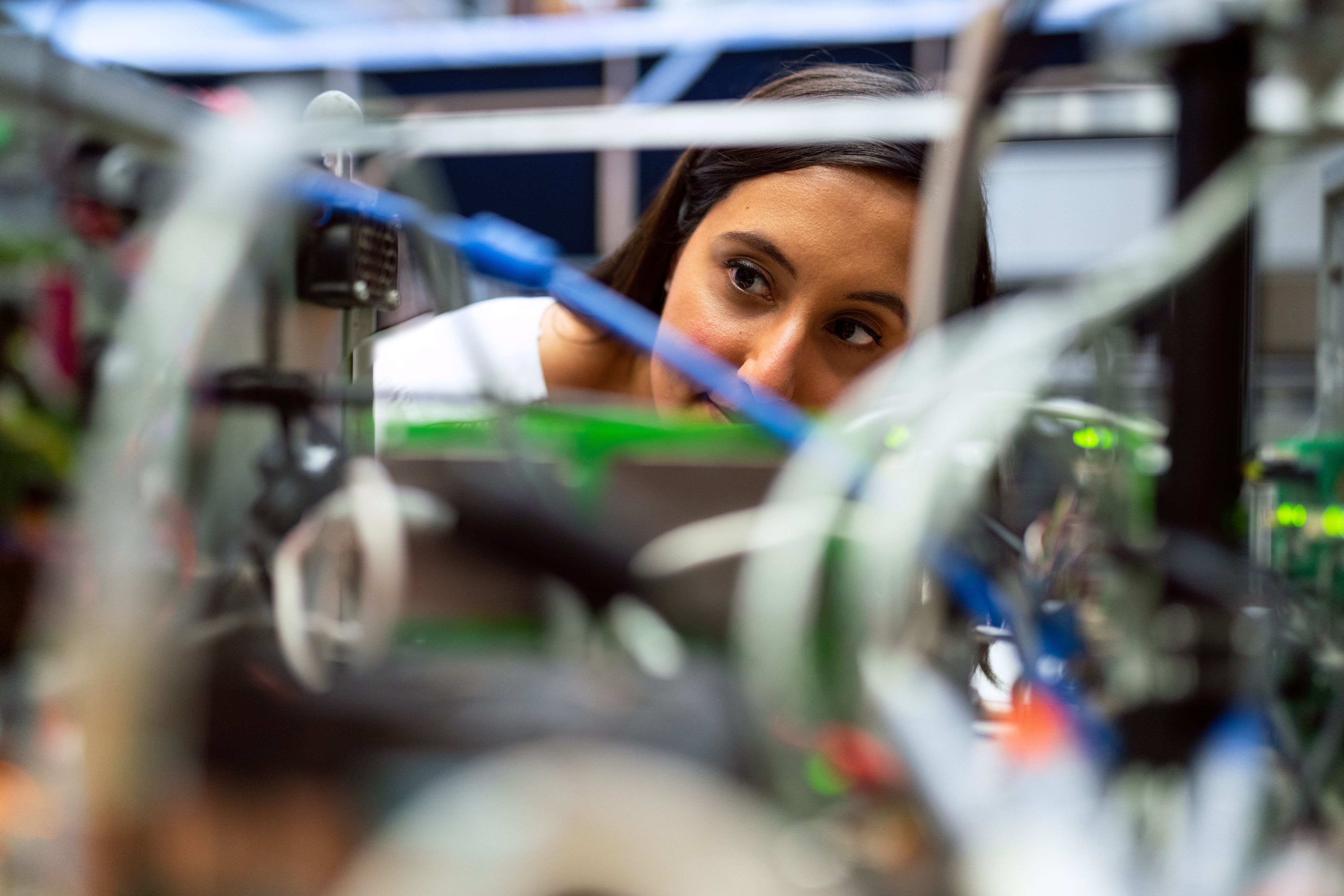 A woman with long brown hair and a lab coat, working on an engineering problem