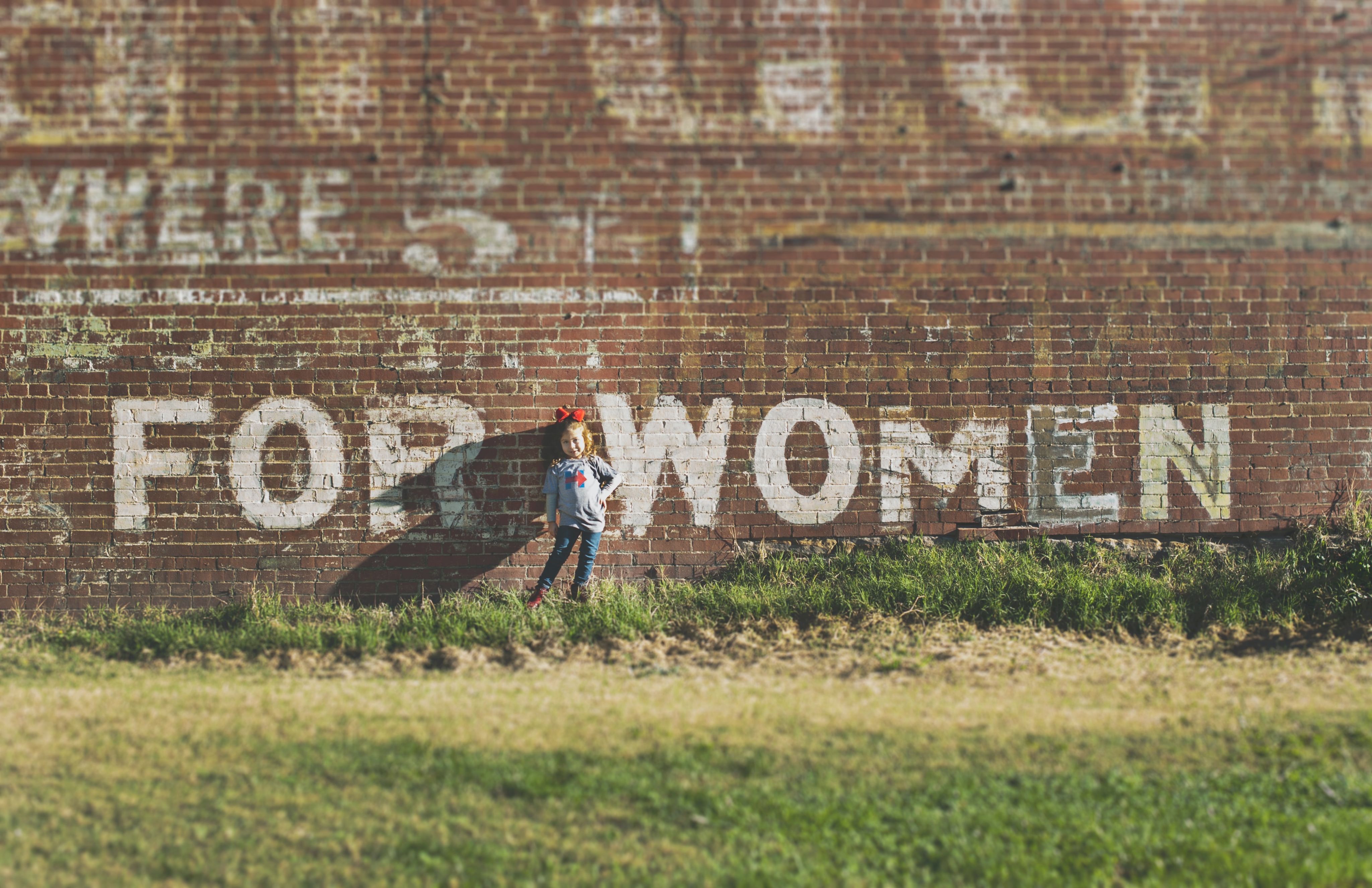 Brick wall with large letters painted in white saying "For Women"