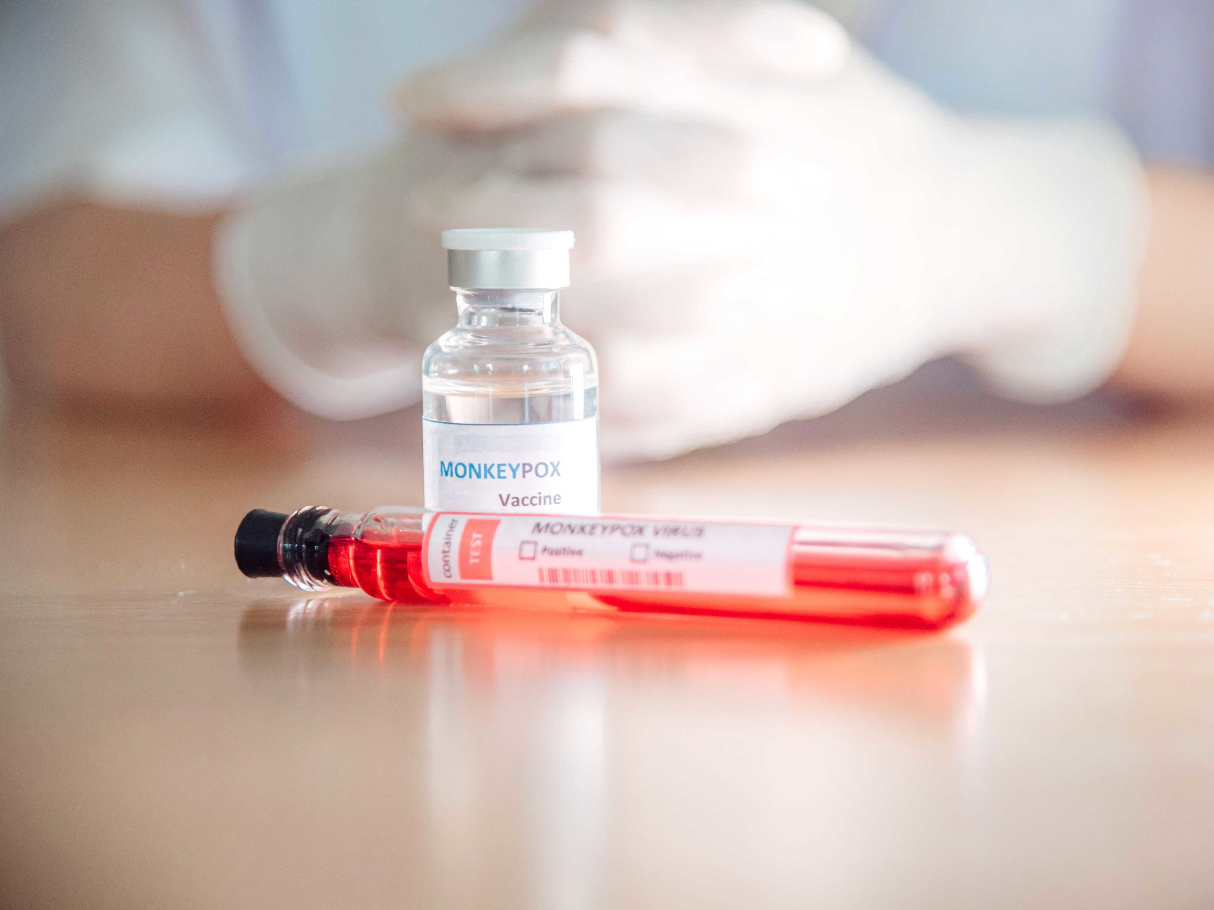 Close up shot of vials containing monkeypox vaccine with person's gloved hands in background.