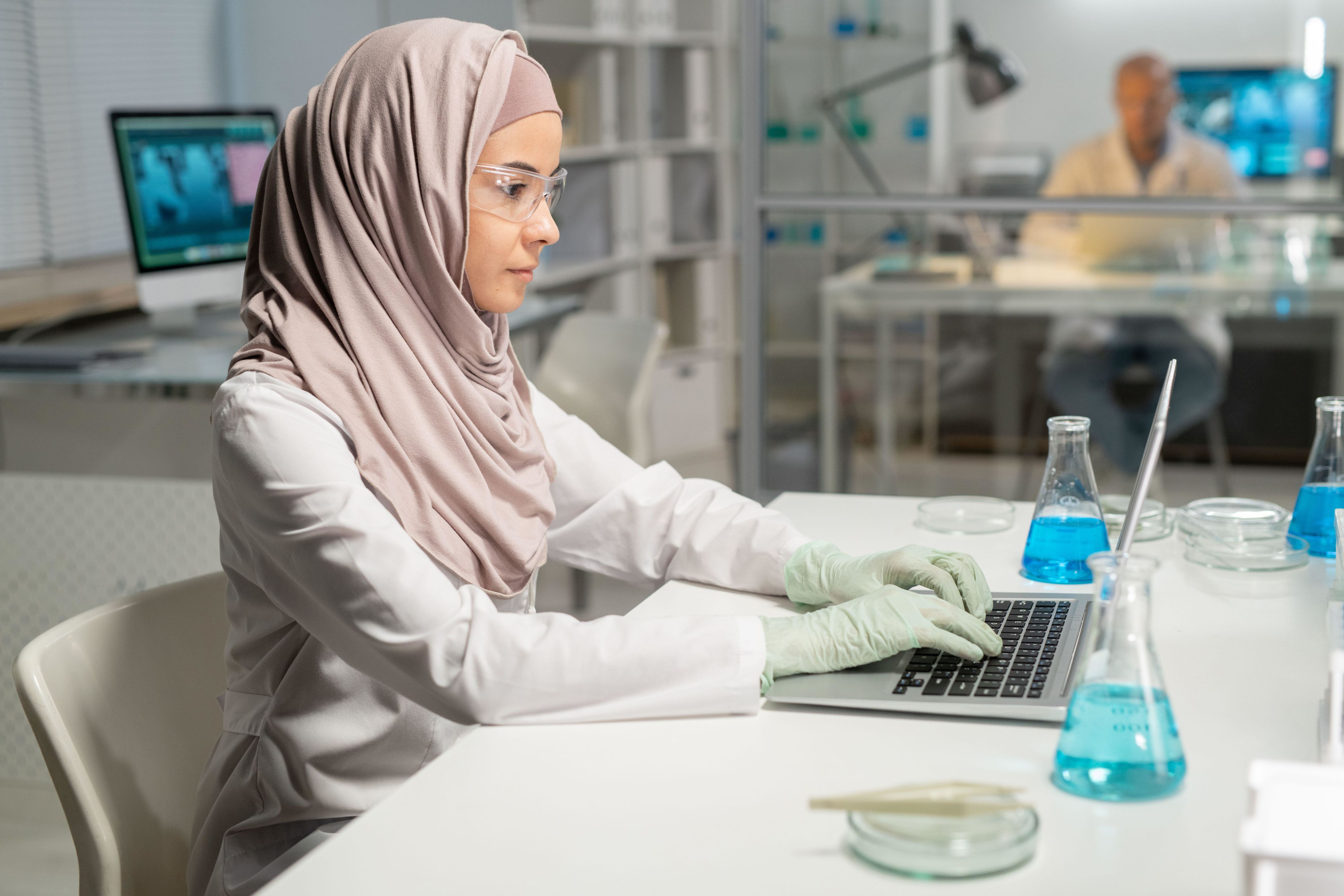 Woman in hijab and protective glasses typing