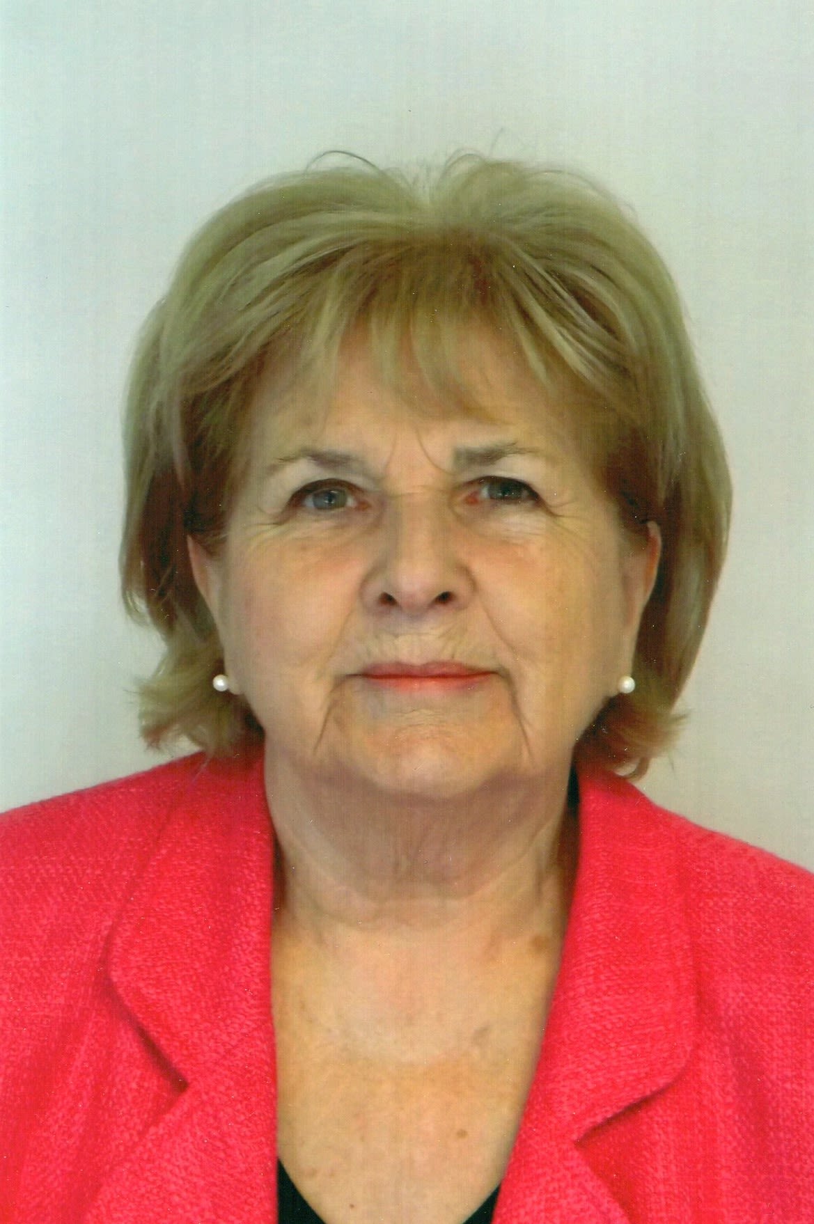 Woman with short blonde hair and a red blazer.