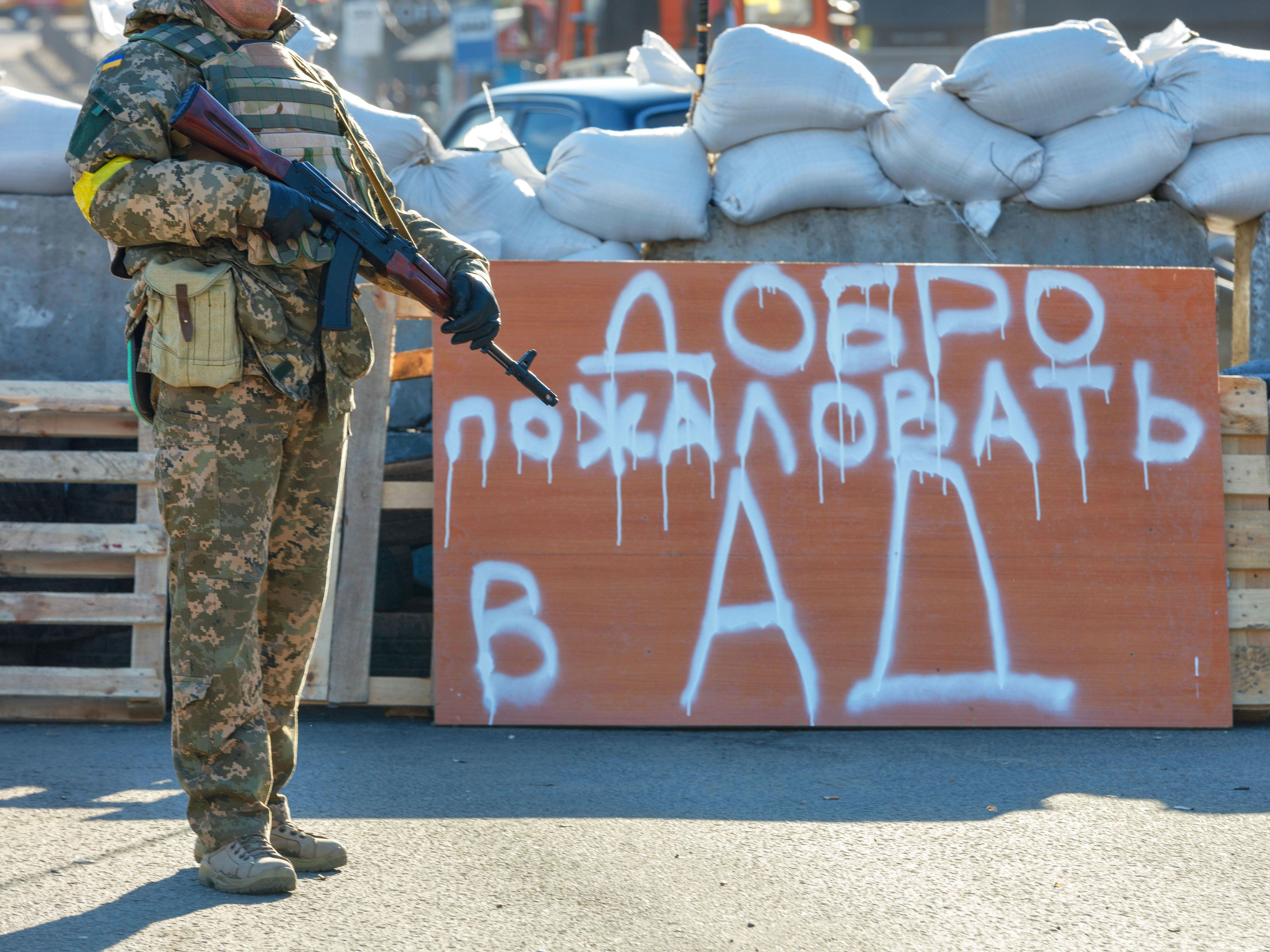 Ukraine soldier standing next to 'Welcome to Hell' sign