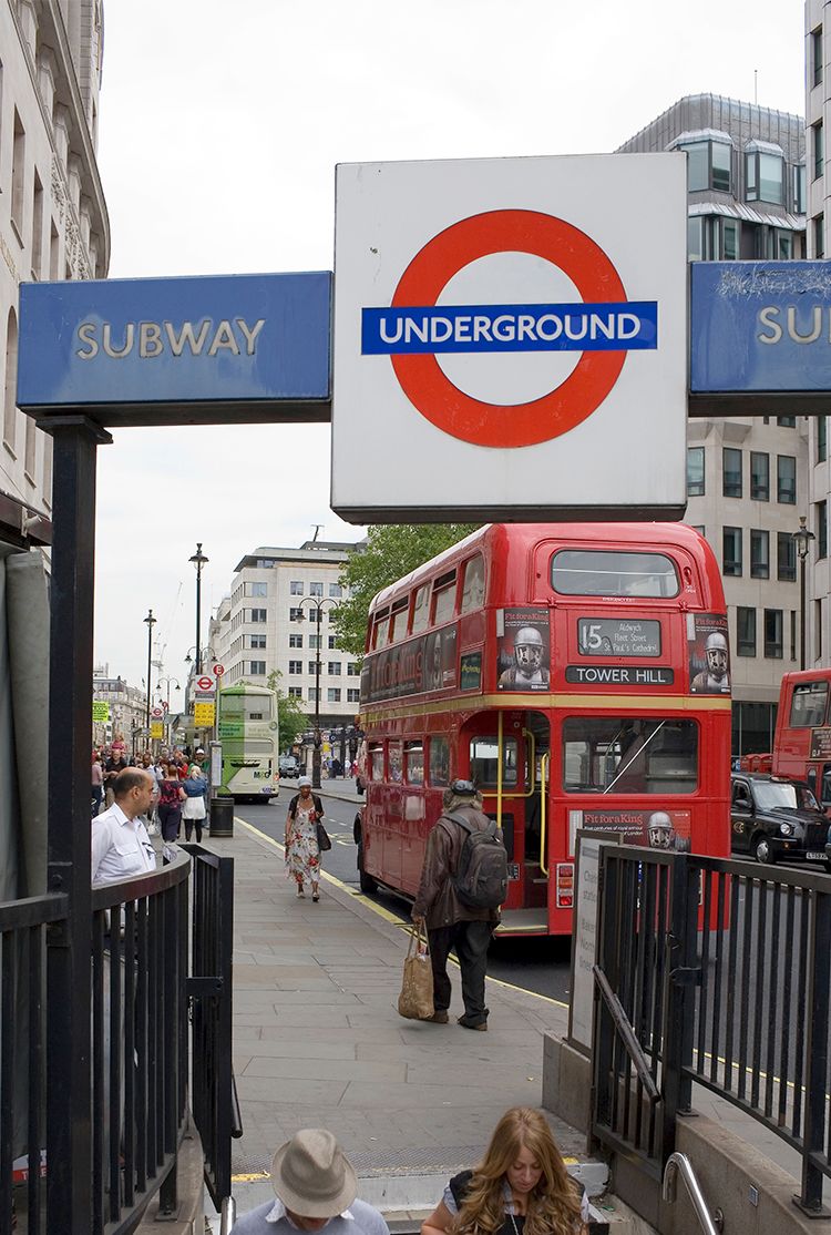 A red London Routemaster bus drives past the subway to the underground entrance at Charing Cross