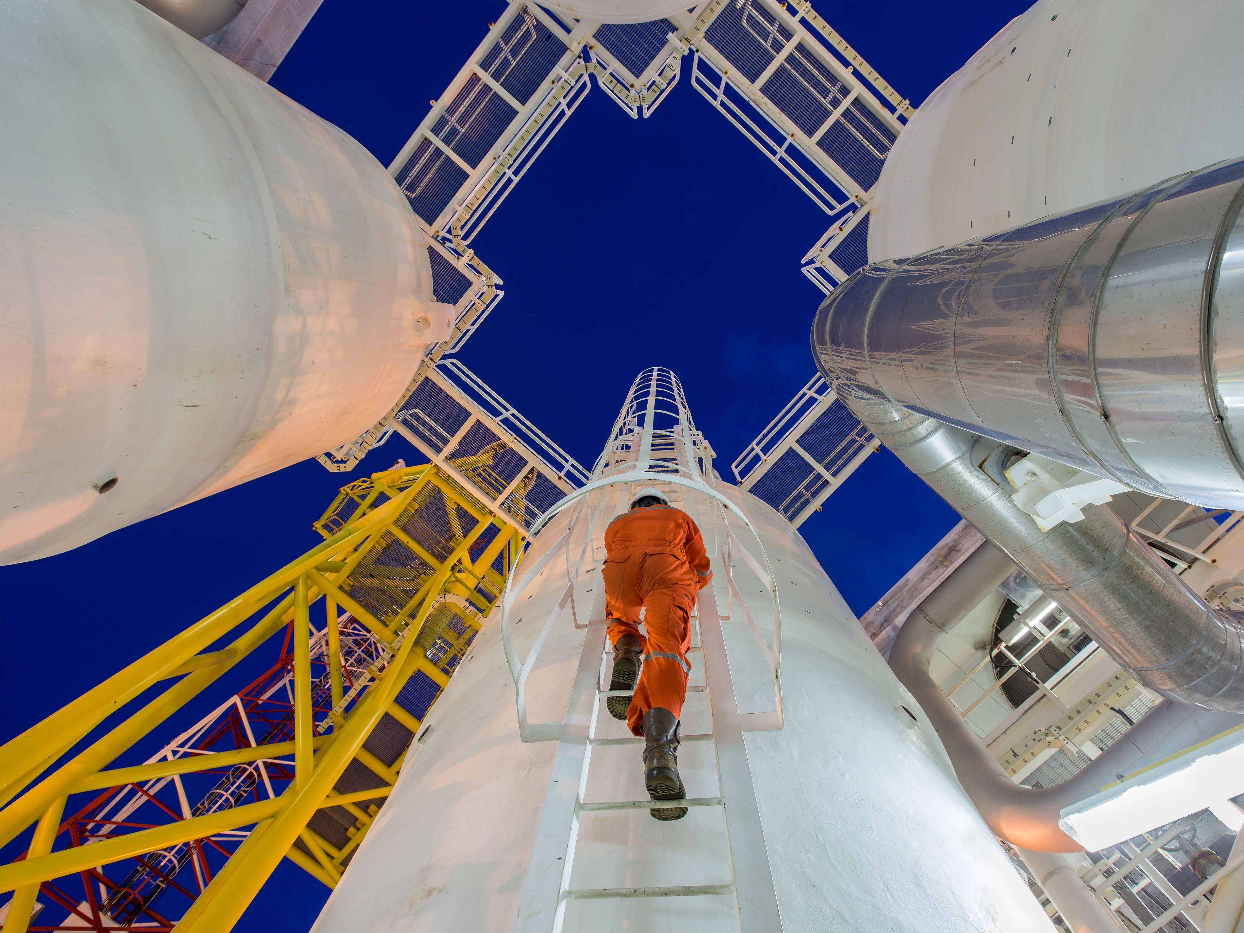 An engineer climbs and oil and gas process plant tower