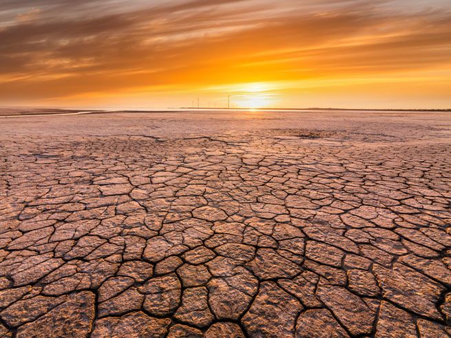 Dry riverbed with sun setting in background