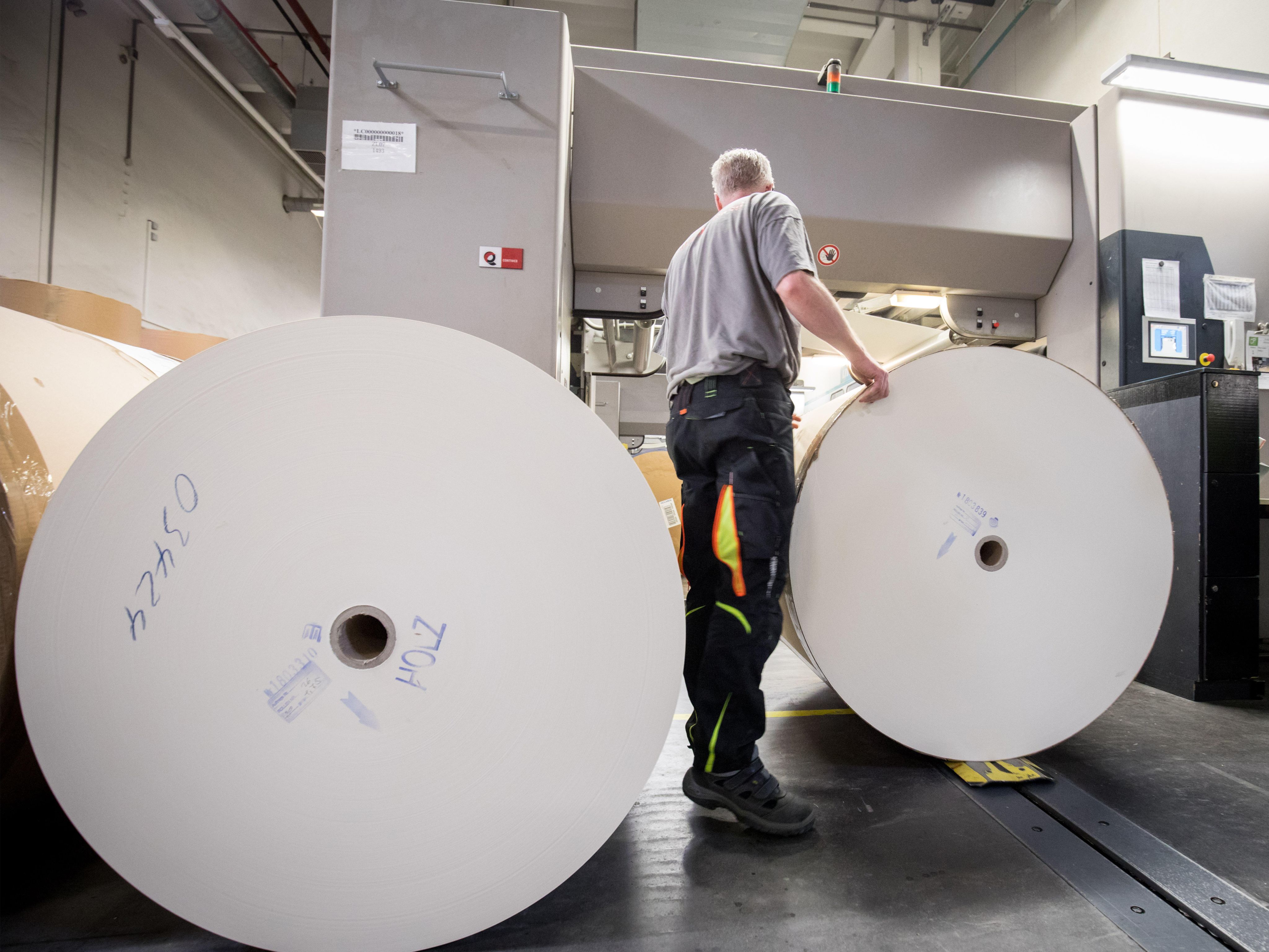 A printer changing two paper rolls for book printing