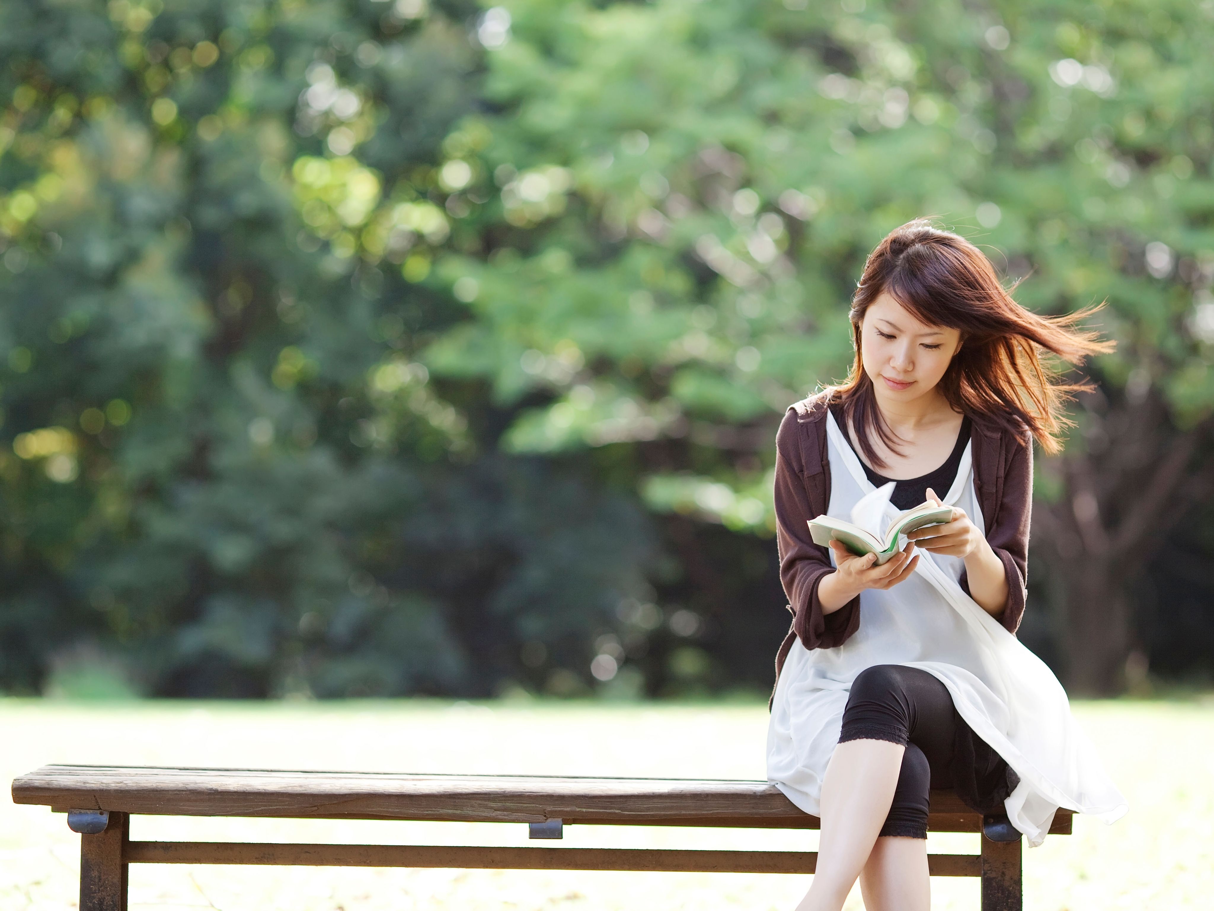 Young woman reading a book sitting on bench
