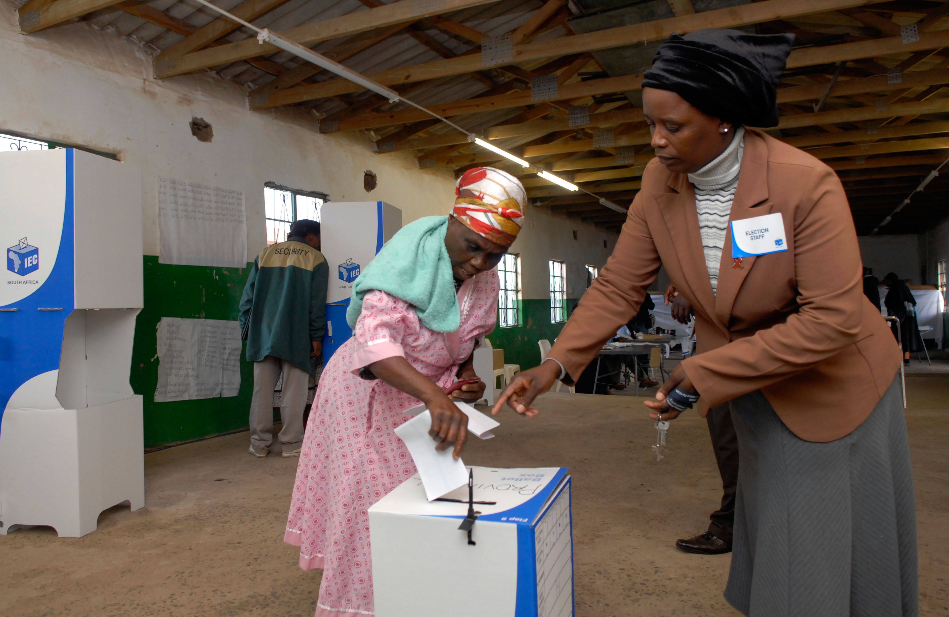 A South African votercasts her ballot with assistance from an election official a voting station in Nkandla area in KwaZulu