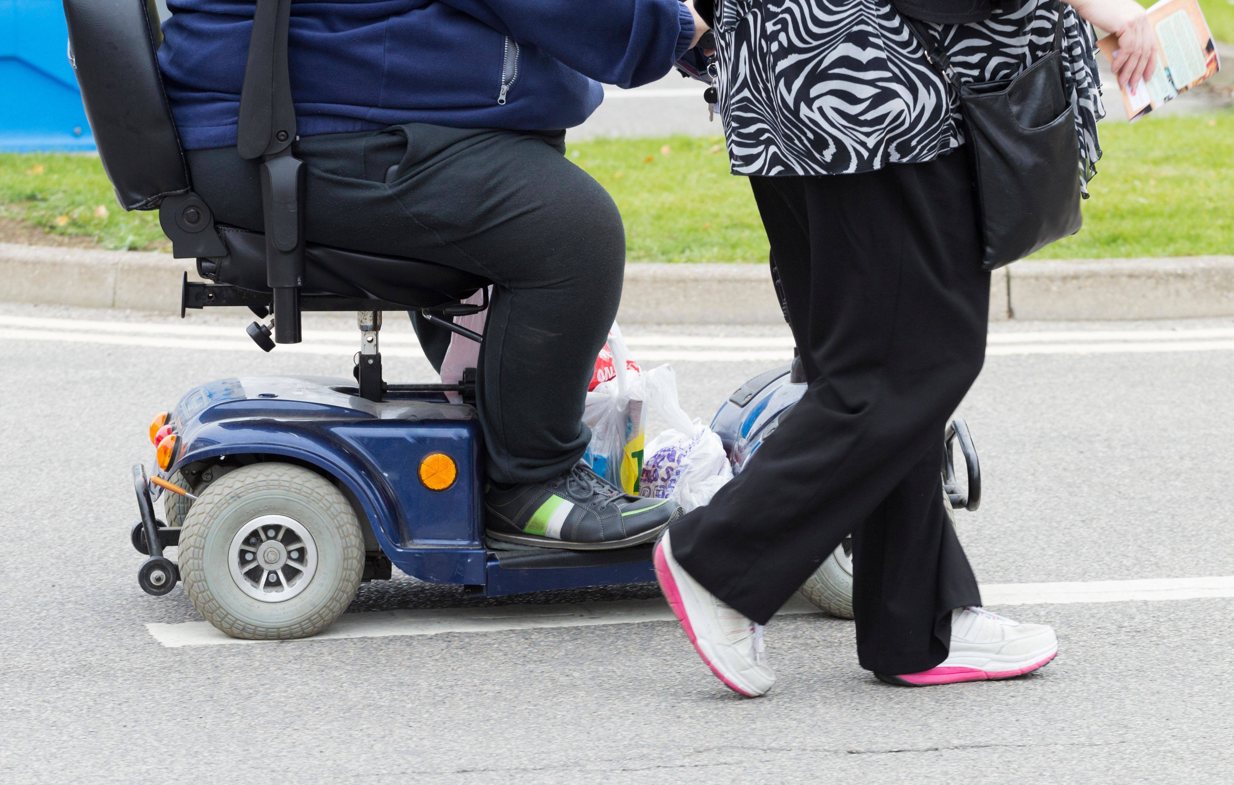 Bottom half of obese man on mobility scooter with pedestrian