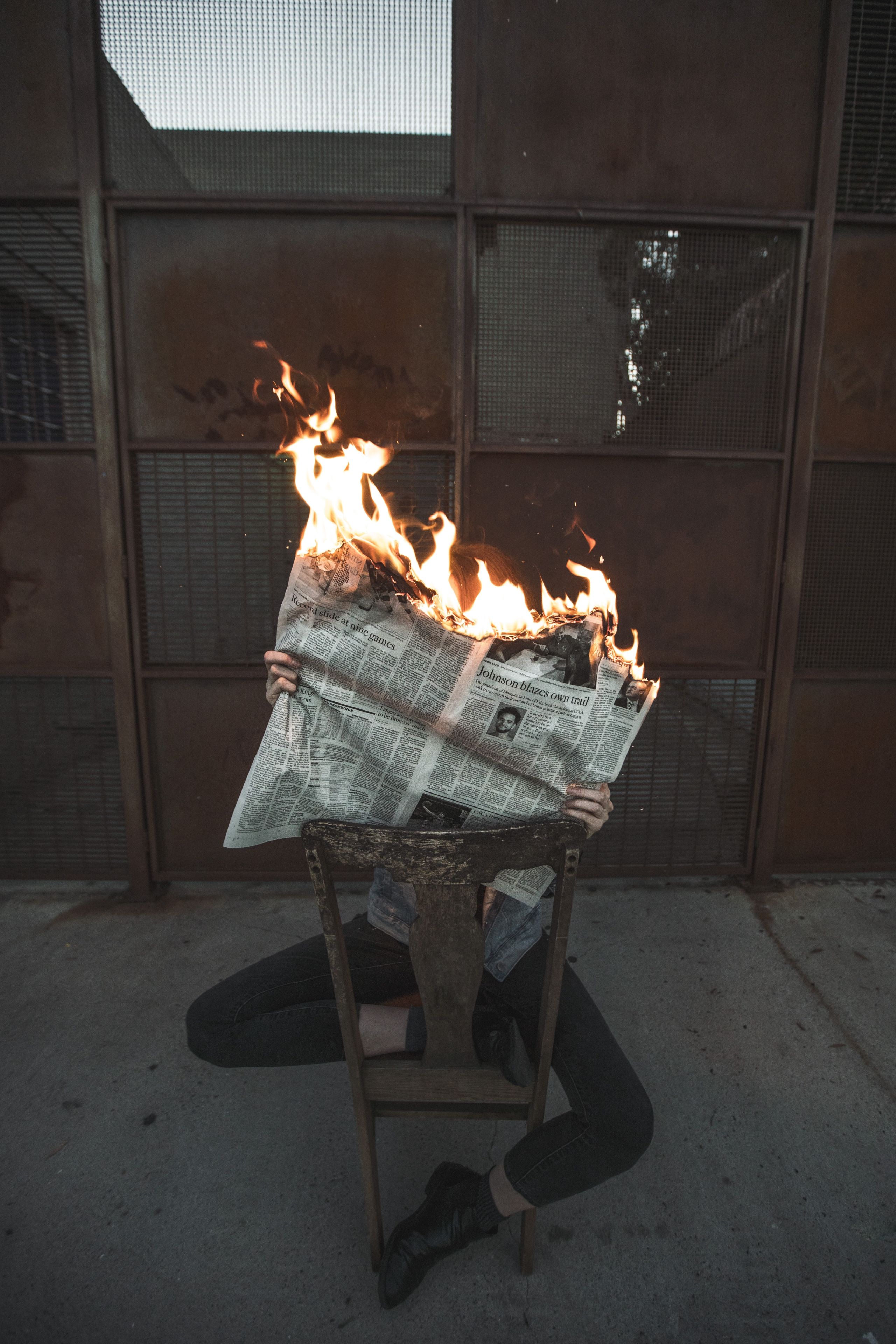 Person reading a newspaper that is on fire.