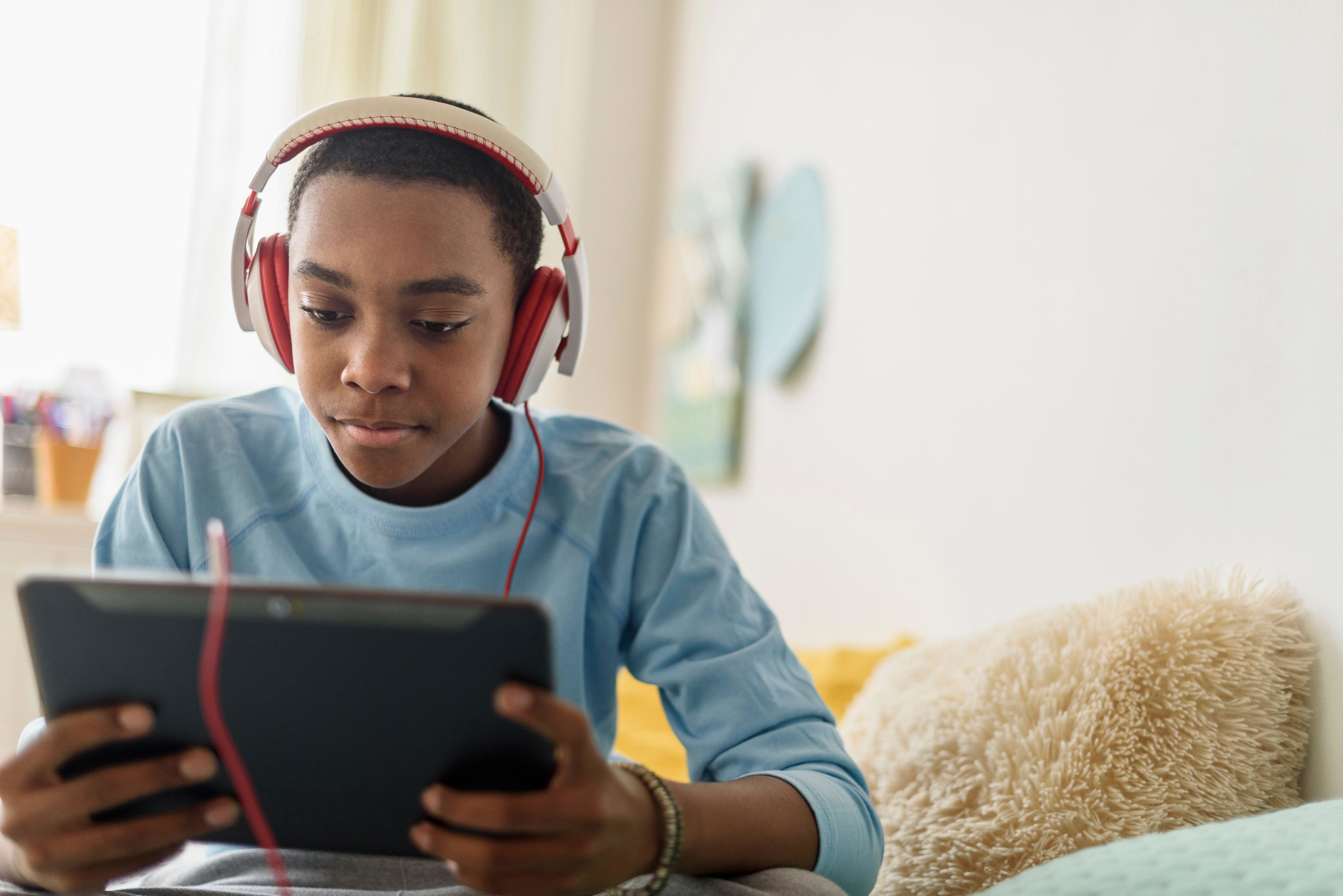Young teen age boy using a tablet while wearing headphones