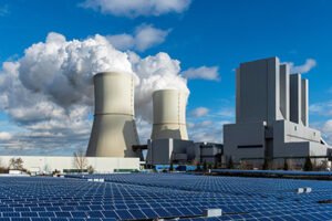 Coal power plant in background with solar panels in foreground