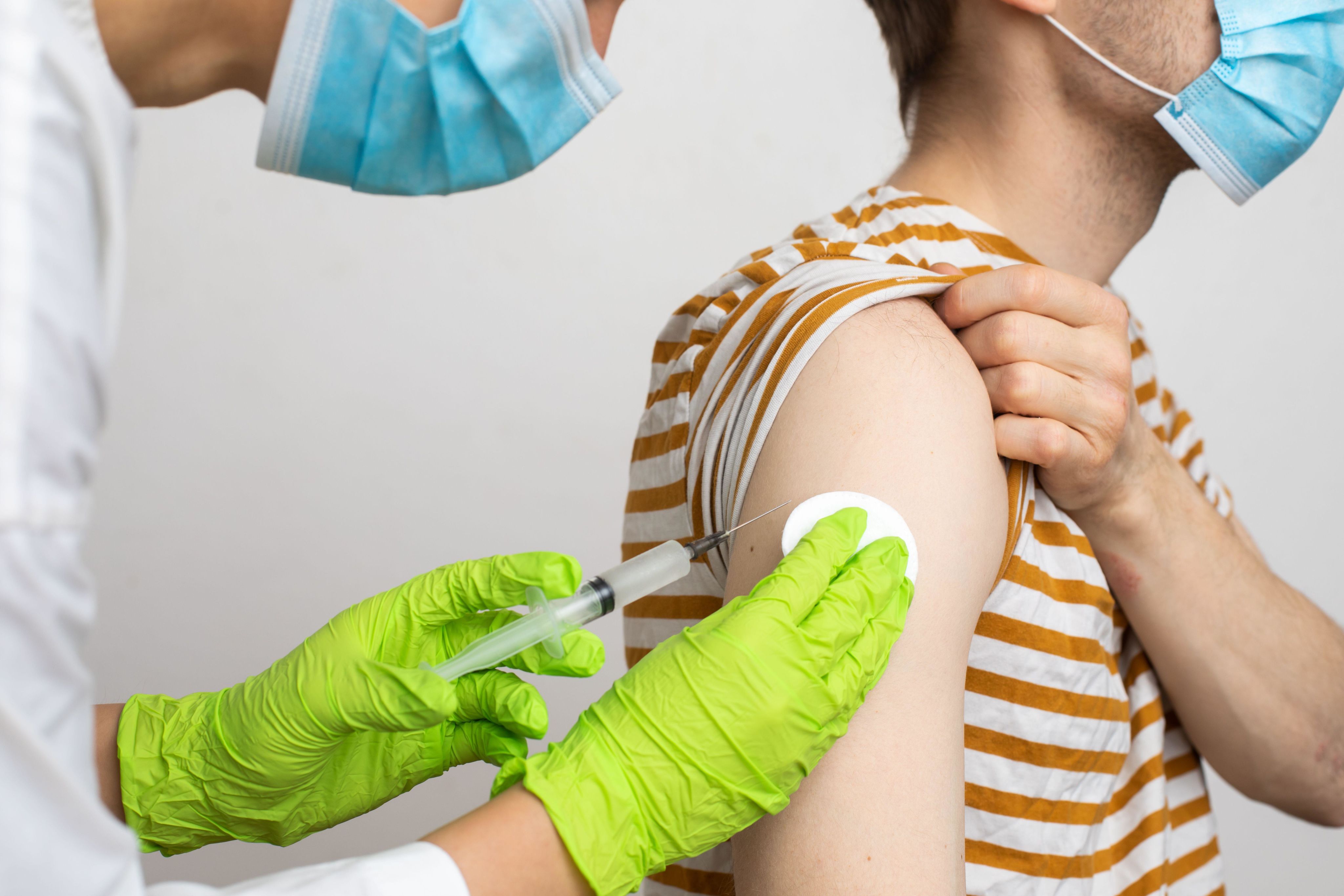 Close up of health professional giving a male the monkeypox vaccine