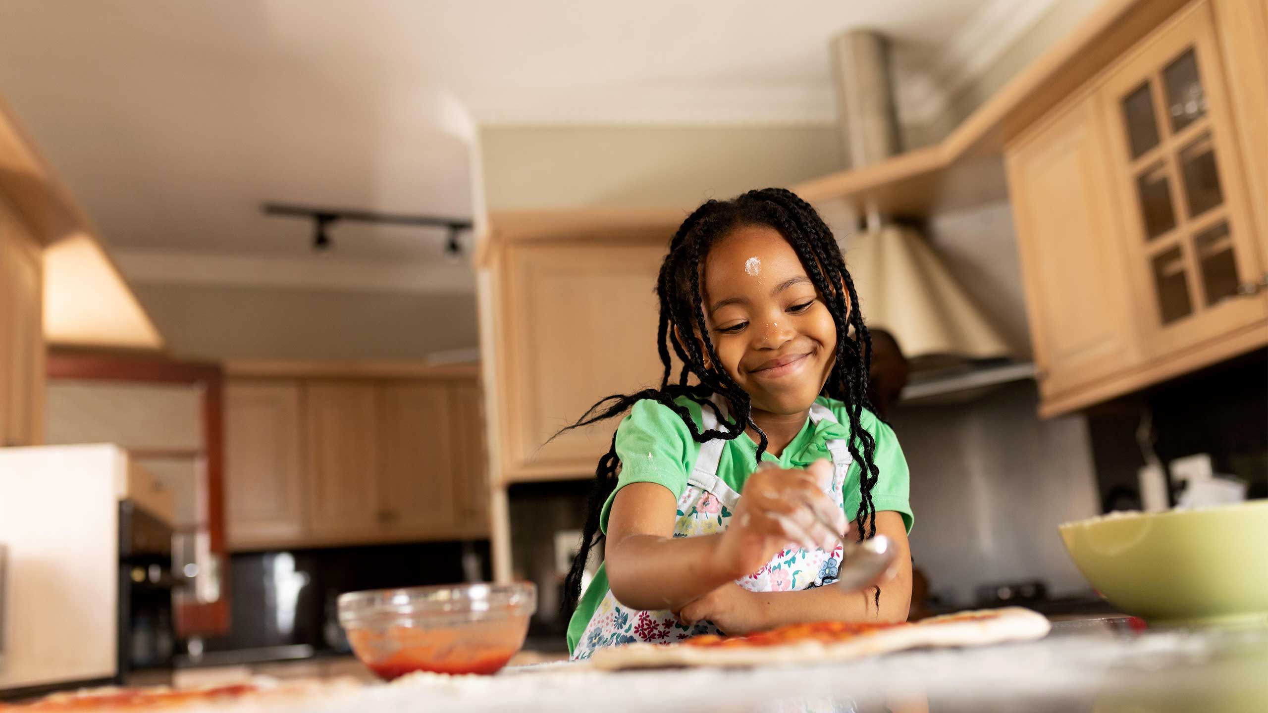 Young girl making pizza at home