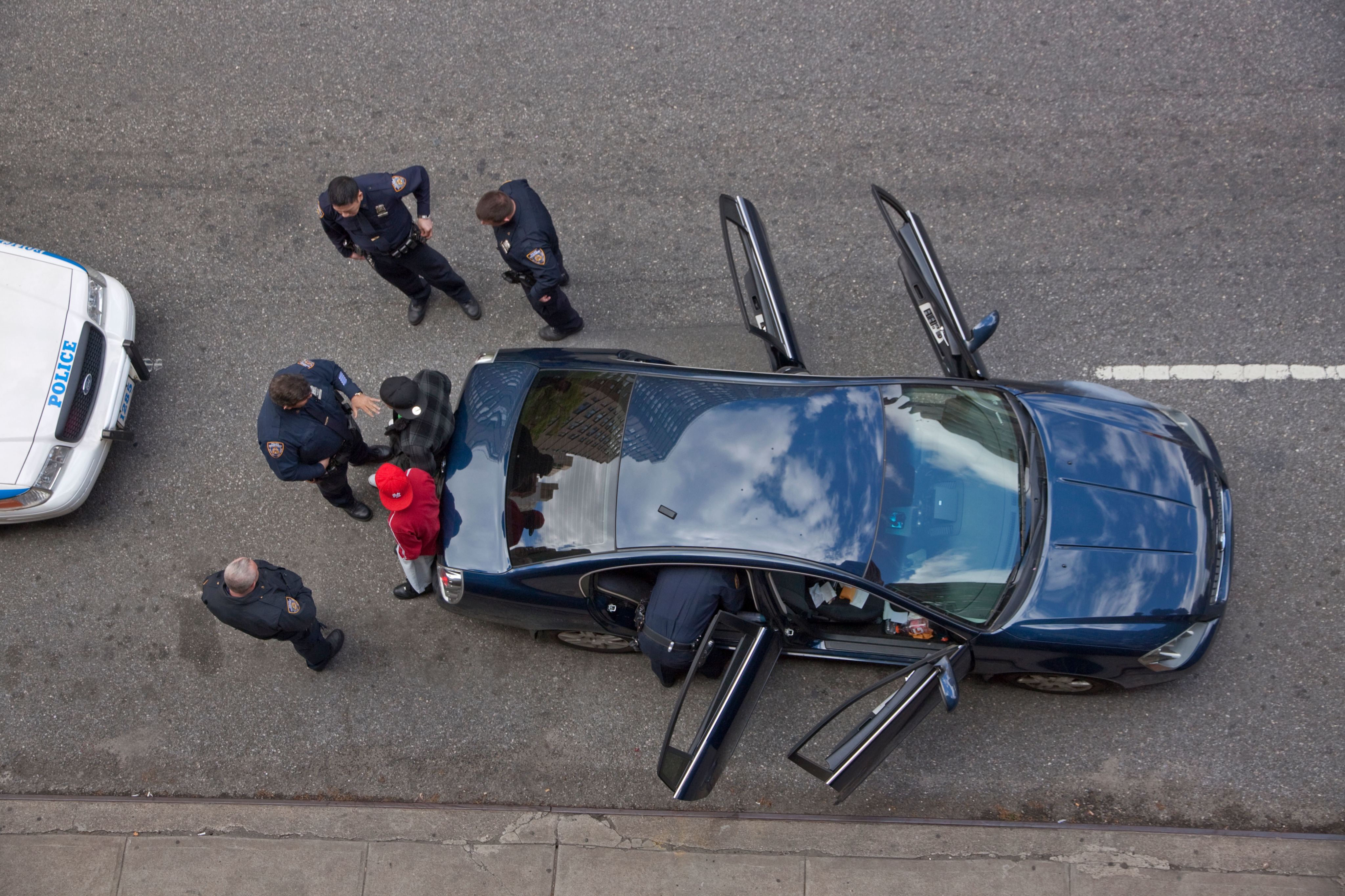 Police officers stop a car with two male suspects in New York City and search their car shot from above