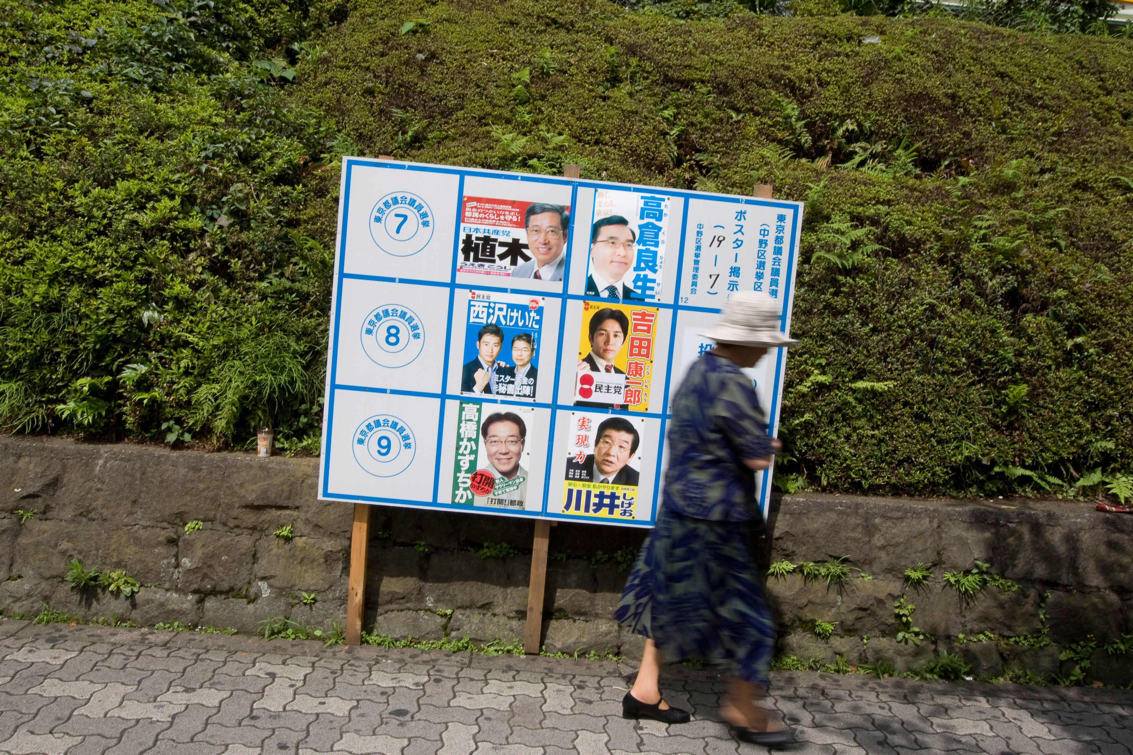 Pedestrians walk past posters for political party candidates in Tokyo