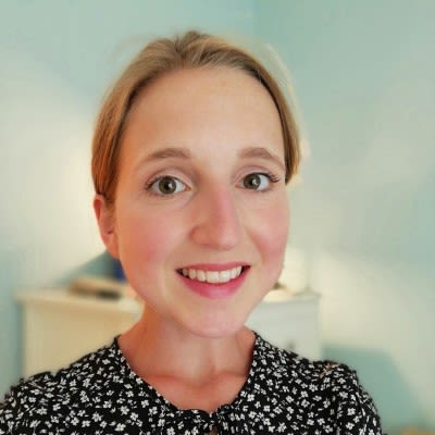 Photo of a blonde woman wearing a black blouse with tiny white flower print.