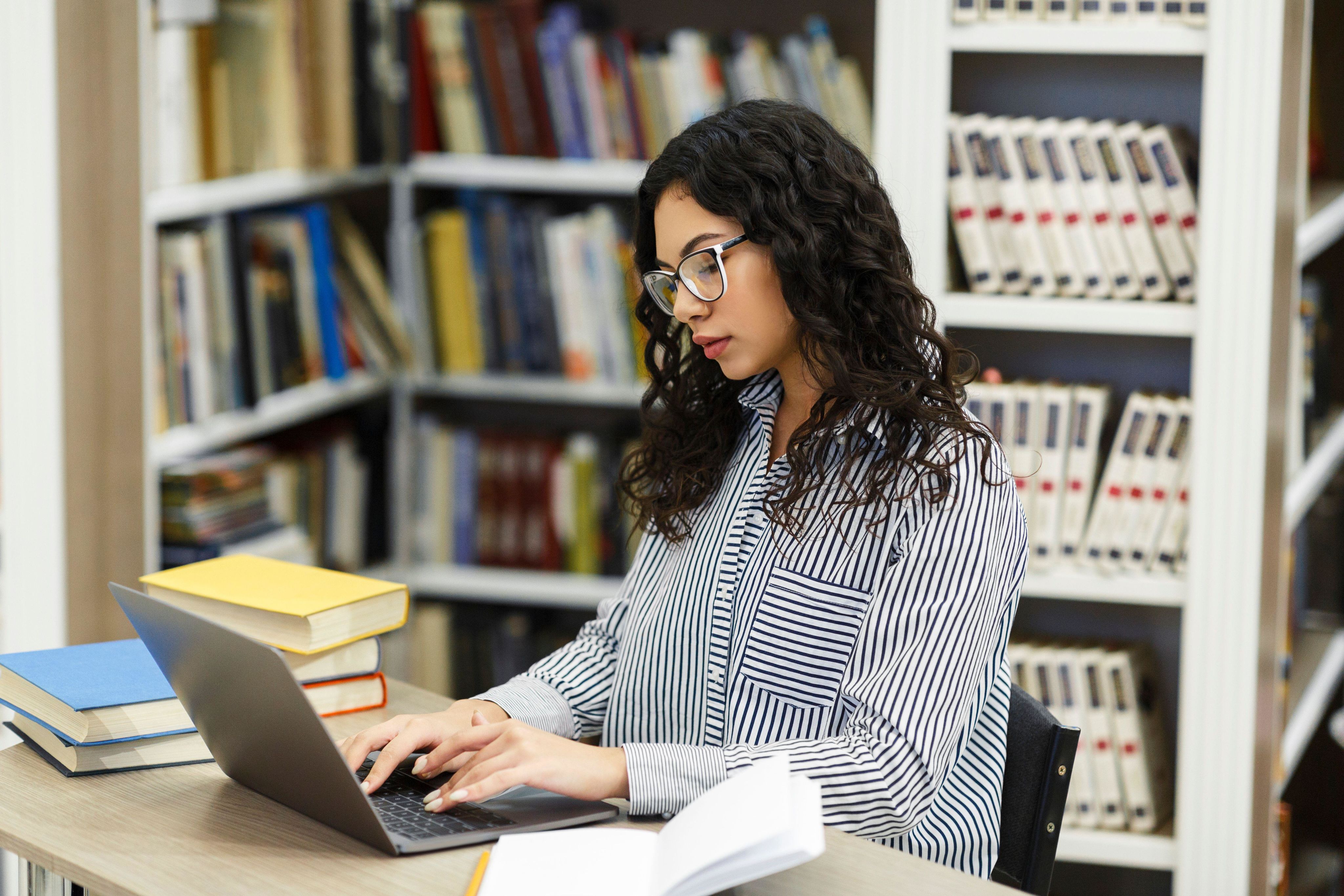 Focused adult sitting at desk in modern library