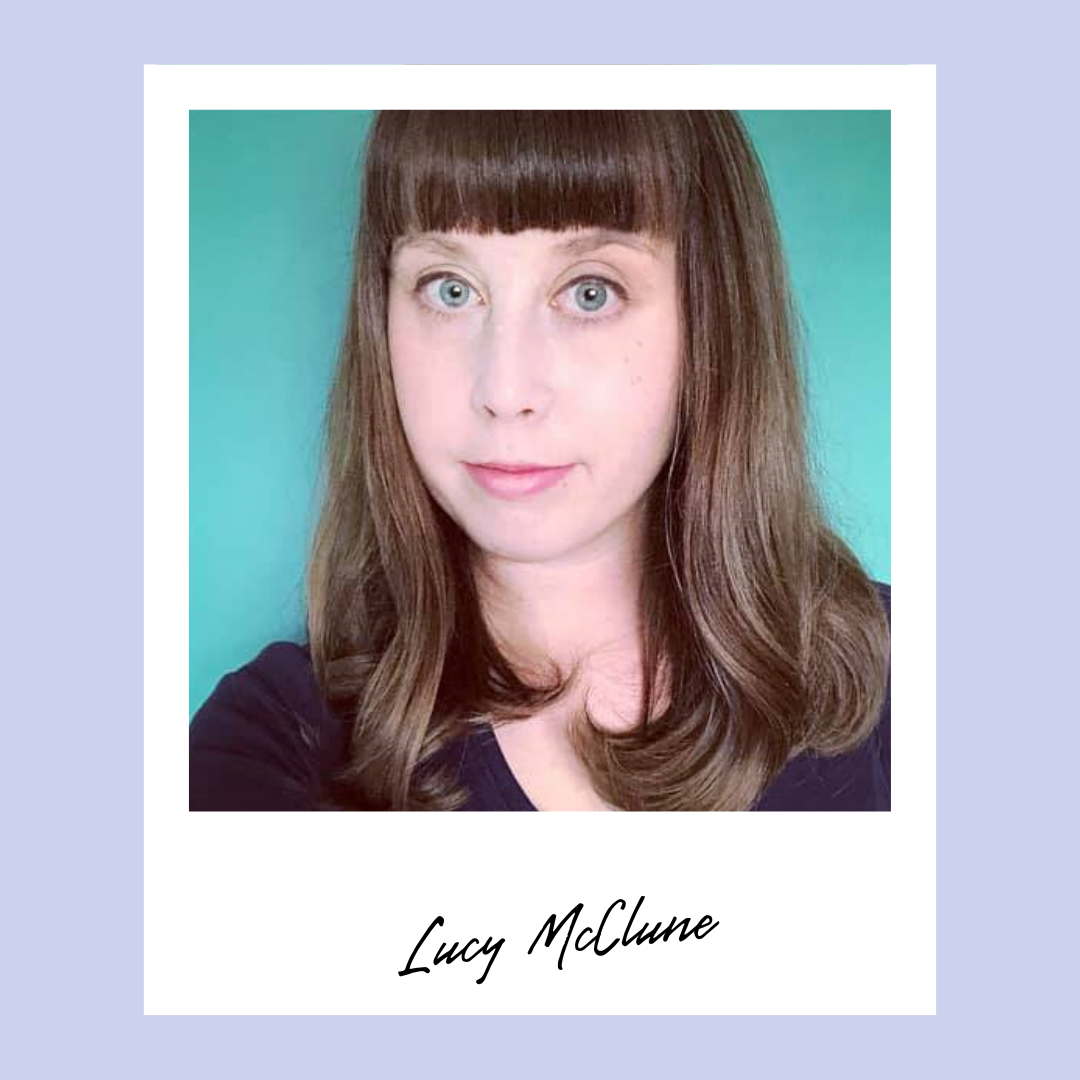Headshot of LucyMcClune wearing a very dark purple V-neck top. She has long auburn hair, blue eyes, and short bangs.