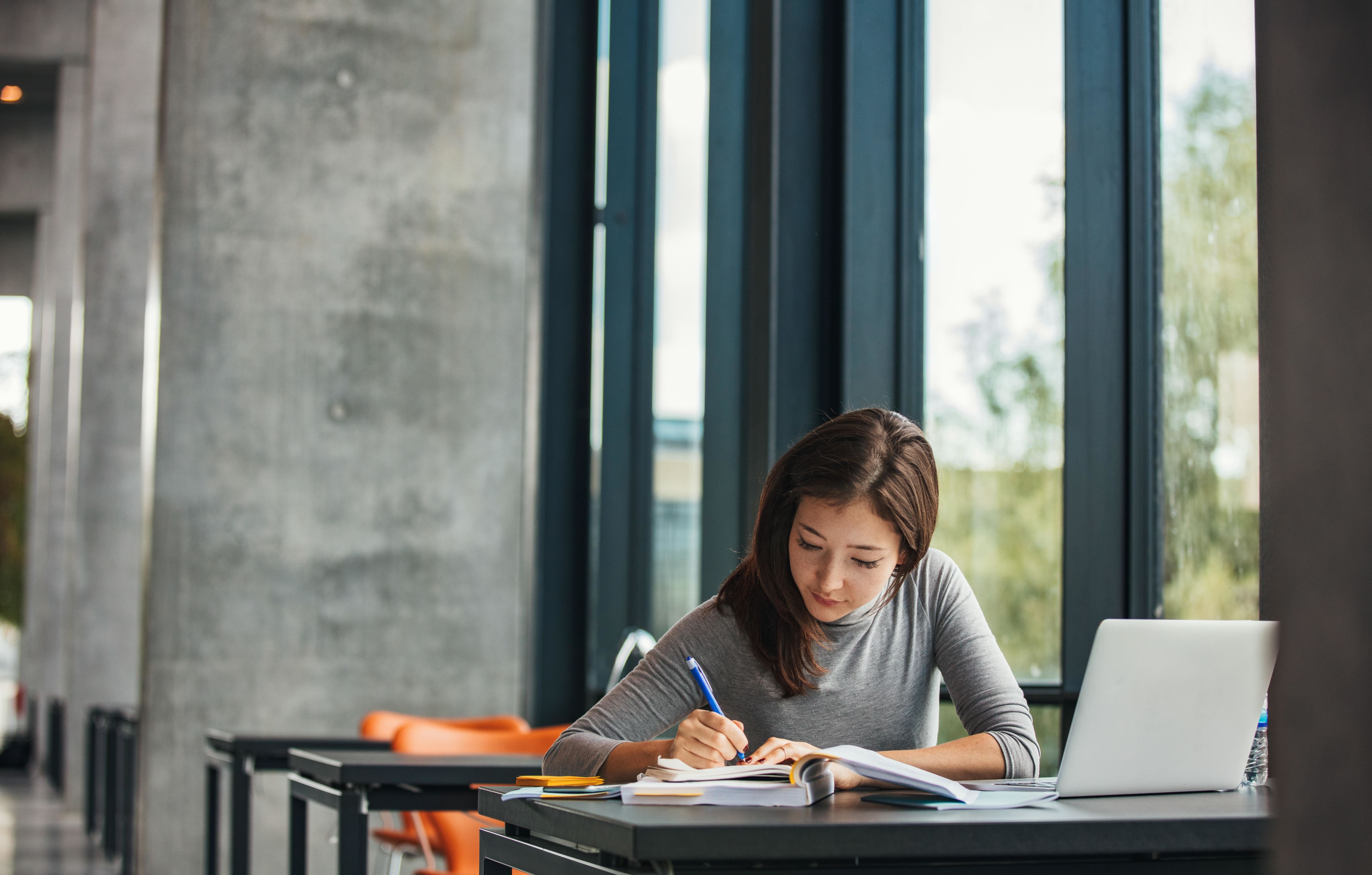 Woman in library with notepad and pen.