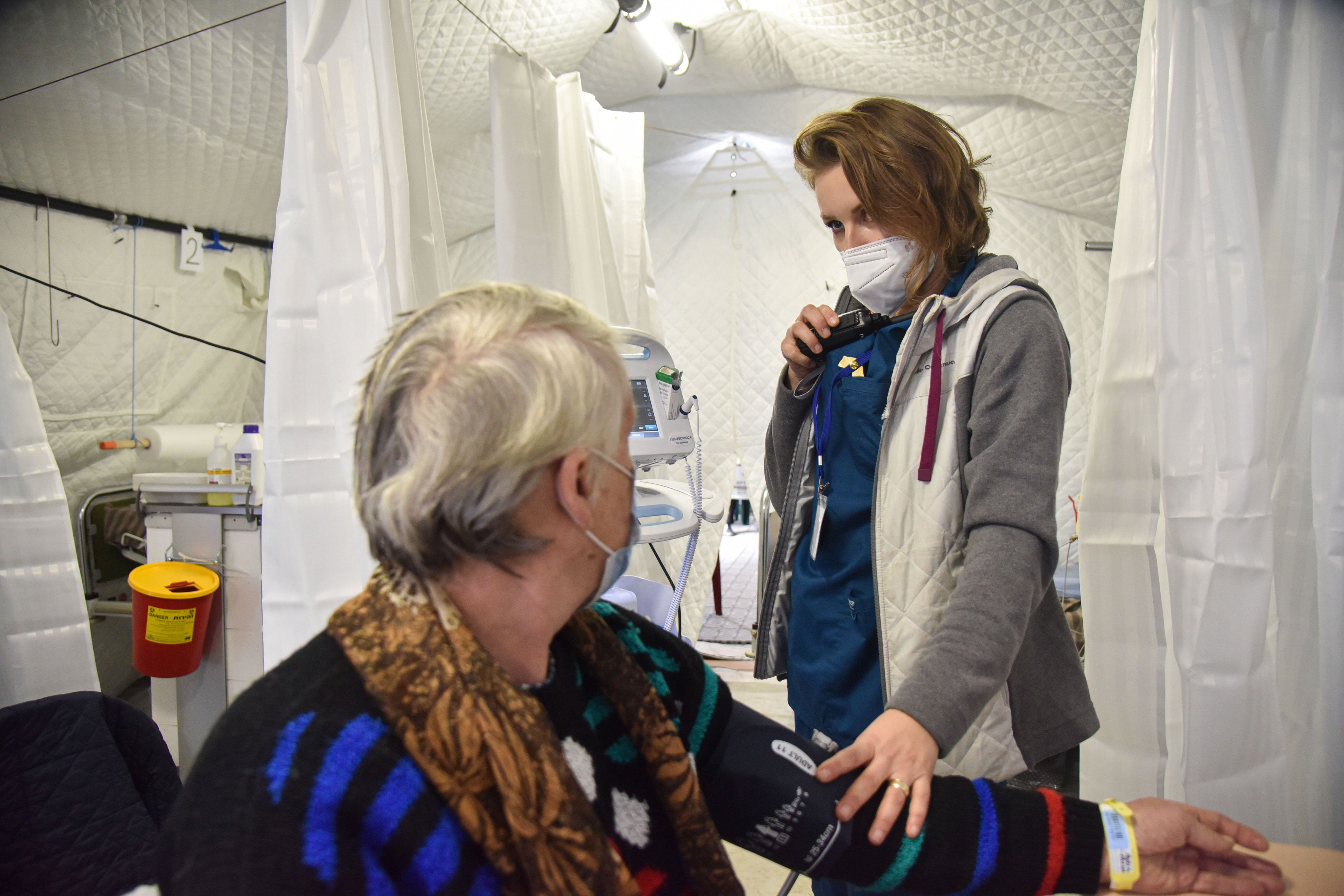 A medical practitioner checking the blood pressure of a patient with a medical device strapped around the patient's arm