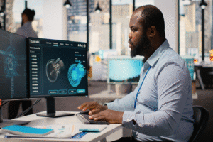 Man at computer, the screen has images of wind turbines being analyzed with AI.