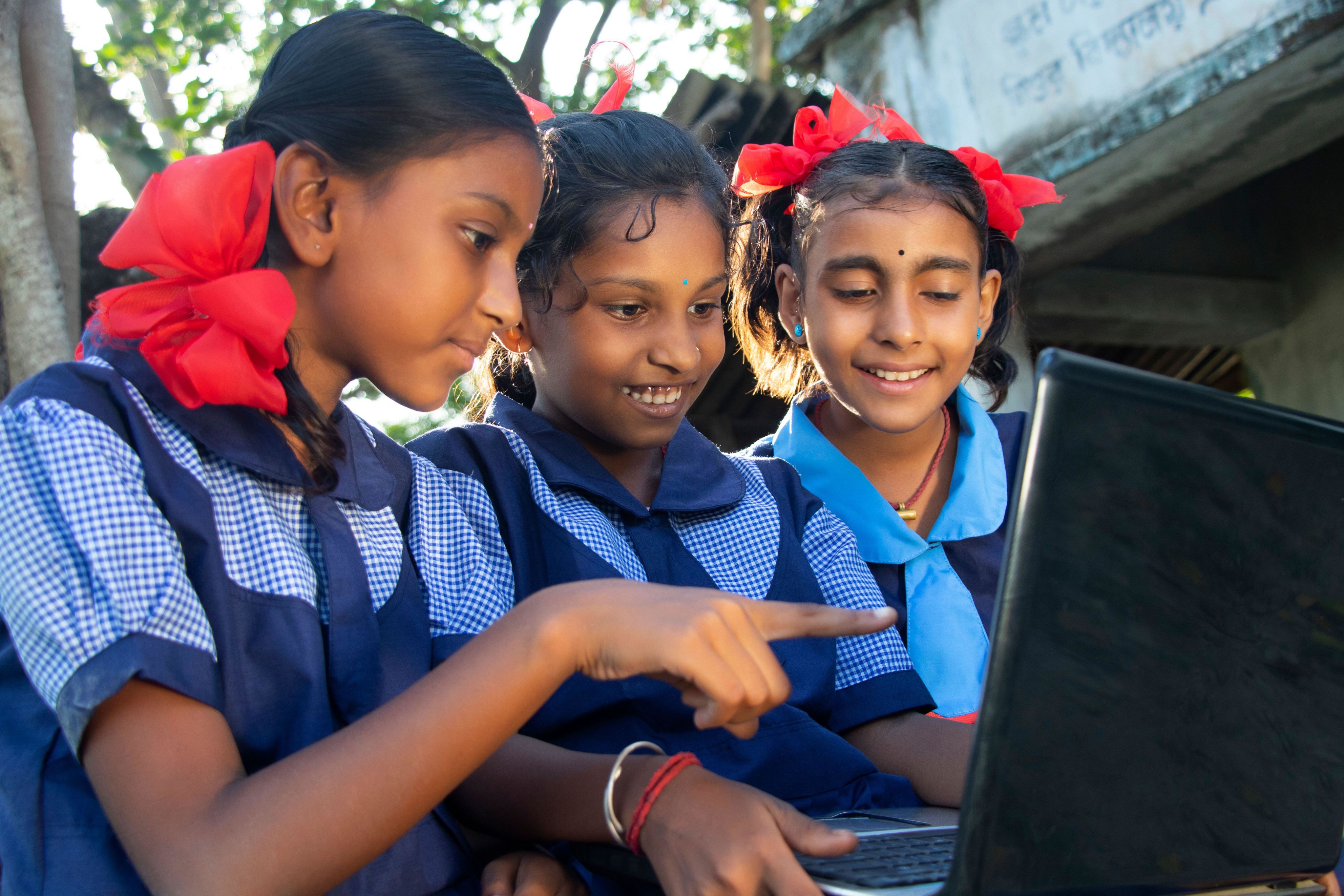 School girls operating laptop computer system at rural area in india